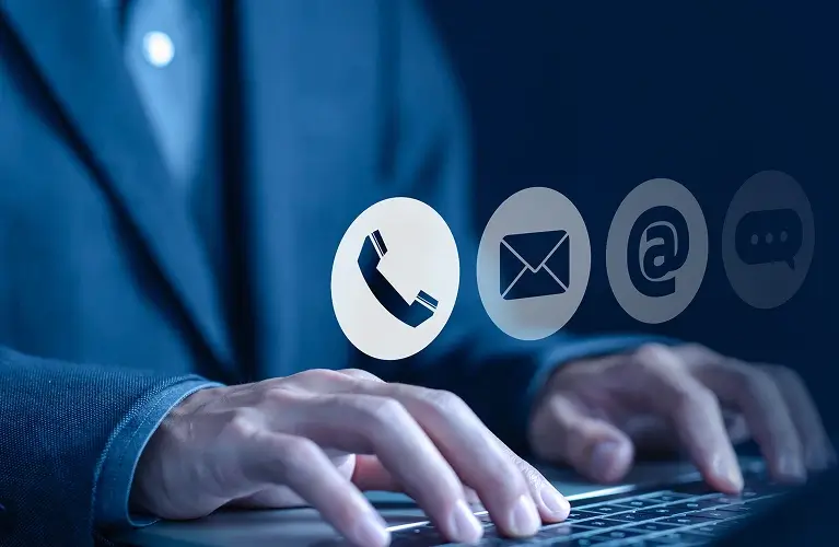 man in a suit types on a laptop displaying various icons, focused on his work in a professional setting