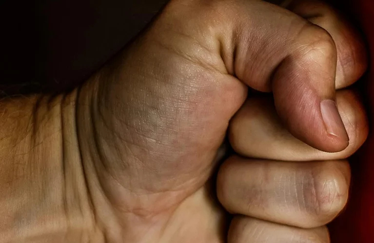A hand holds a vibrant red object, showcasing its color and texture against a neutral background