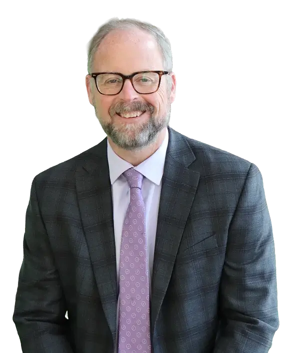 Eric Herbert, a man with glasses, wearing a purple tie, poses for the camera