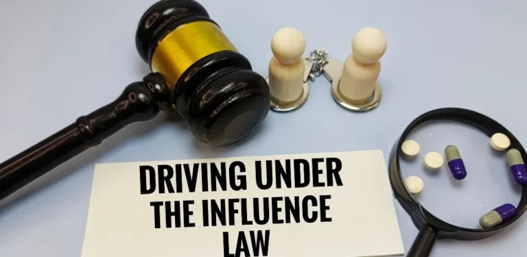 Wooden judge’s gavel, two wooden figurines with handcuffs, magnifying glass with pills, and a paper stating "Driving Under The Influence Law".