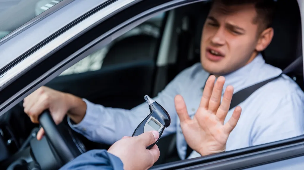Man inside car refusing to take breathalyzer test offered by officer.